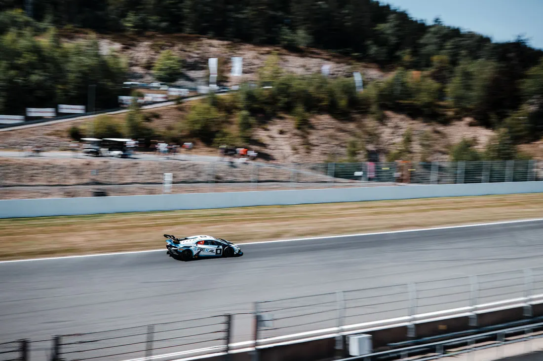 Un coche de carreras a gran velocidad en un circuito rodeado de colinas