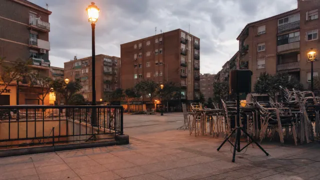 Plaza rodeada de edificios de viviendas con farolas encendidas al atardecer