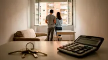 Dos personas observan la ciudad desde la ventana de un apartamento con vistas