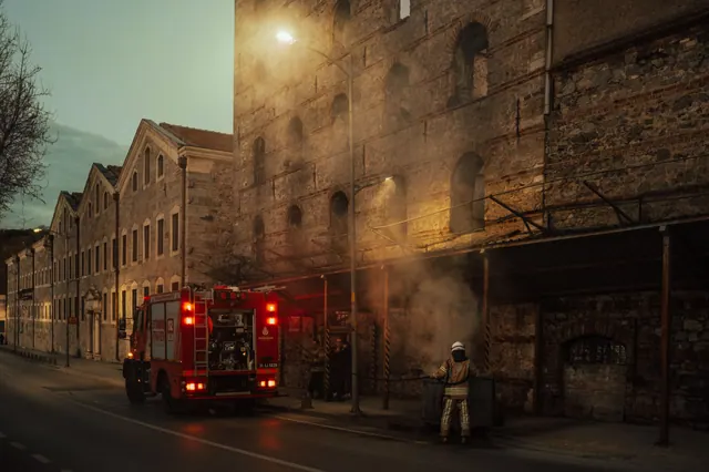 Bomberos con equipo de protección trabajando en la extinción de un incendio en una calle estrecha
