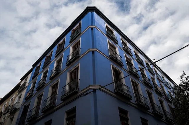 Edificio de esquina con fachada azul y balcones de hierro forjado en estilo arquitectónico clásico