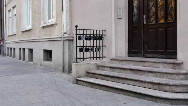 Entrada de un edificio histórico con escalinata de piedra y puerta de madera oscura