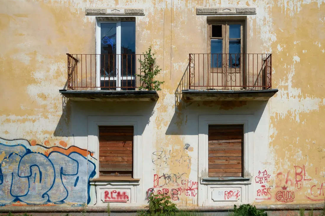 Imagen ilustrativa: Fachada abandonada con balcones y ventanas tapiadas cubierta de grafitis