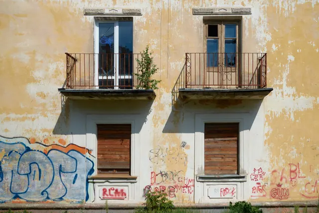 Imagen ilustrativa: Fachada abandonada con balcones y ventanas tapiadas cubierta de grafitis