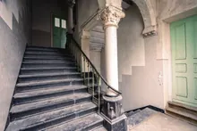 Imagen ilustrativa: Escalera antigua con columnas y puertas verdes