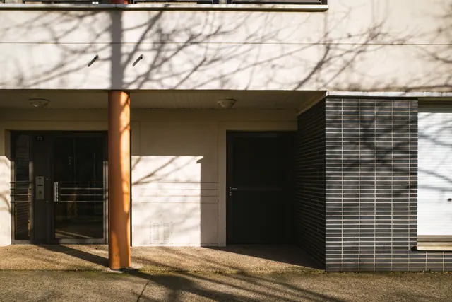 Fachada de un edificio de viviendas con sombras de árboles