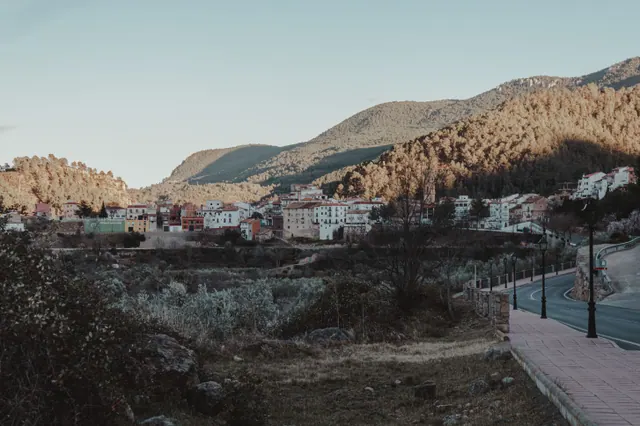 Vista de un pequeño pueblo de montaña con casas de piedra y un edificio consistorial en la plaza principal