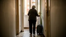 Una persona mayor camina por un pasillo con una maleta