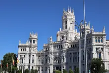 Fachada de un imponente edificio histórico de piedra clara con torres, ventanales y detalles ornamentales