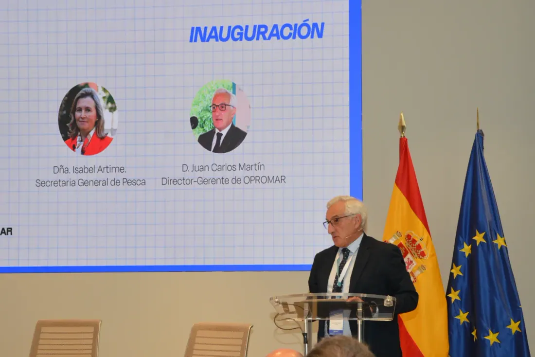 Un hombre habla en un atril junto a las banderas de España y la Unión Europea