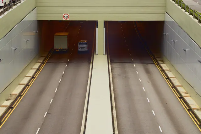 Boca de un túnel urbano de carretera recién construido con vallas de obra y asfalto nuevo