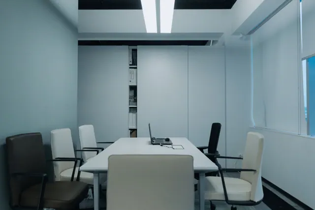 Sala de reuniones vacía con mesa, sillas y un portátil