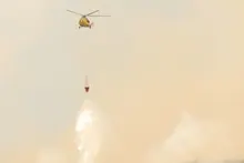 Helicóptero de extinción de incendios descargando agua sobre una zona con humo
