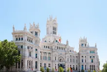 Fachada de un edificio monumental de piedra clara con torres, arcos y grandes ventanales bajo el cielo
