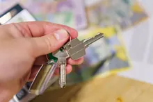 Una mano sostiene unas llaves sobre una mesa con documentos de fondo