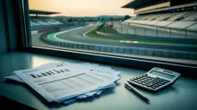 Documentos y calculadora sobre escritorio con vista a circuito de carreras