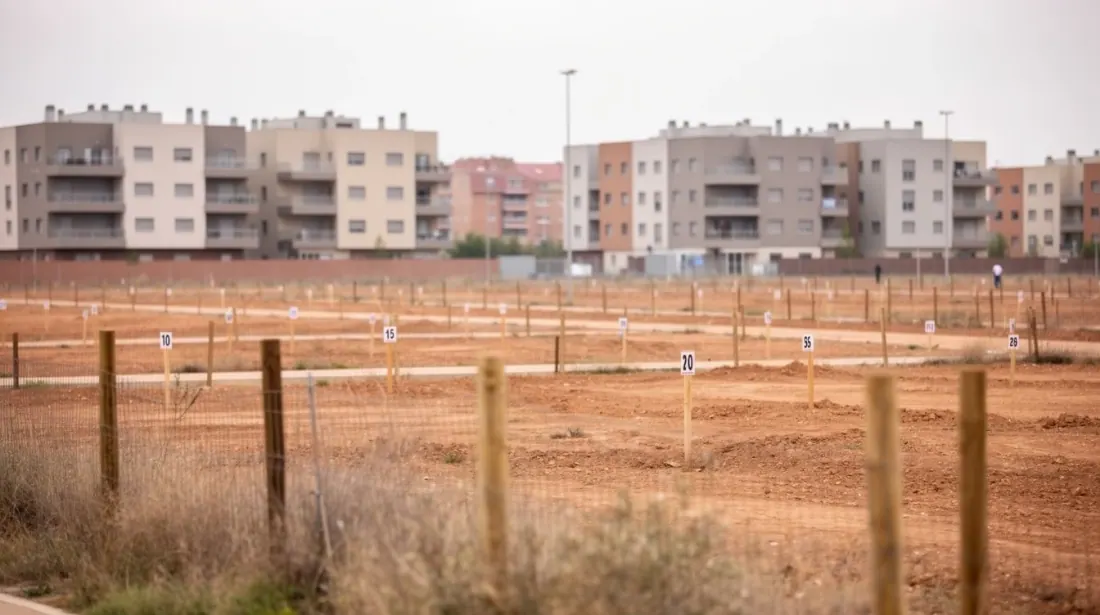 Terreno urbanizable vallado frente a bloques de viviendas residenciales