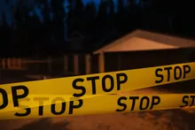 Cinta policial amarilla con la palabra STOP frente a una vivienda de noche