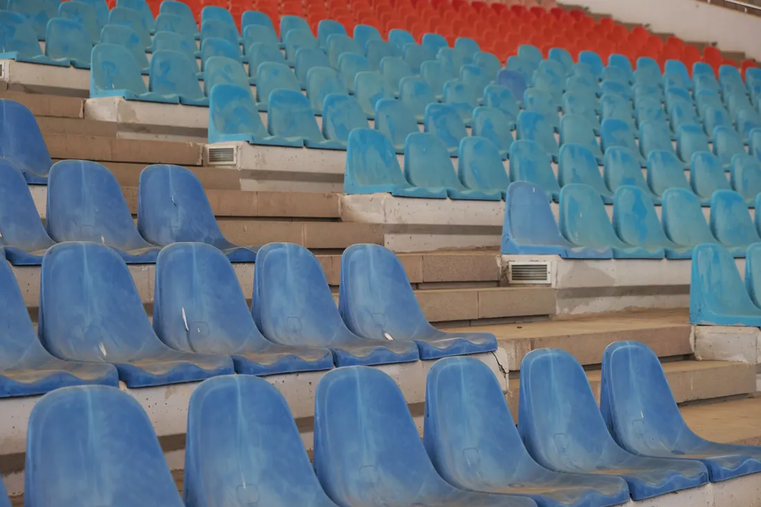 Gradas vacías de un estadio con asientos azules y rojos