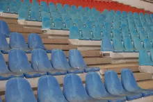 Gradas vacías de un estadio con asientos azules y rojos