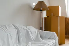 Sofá cubierto con una sábana junto a cajas de mudanza