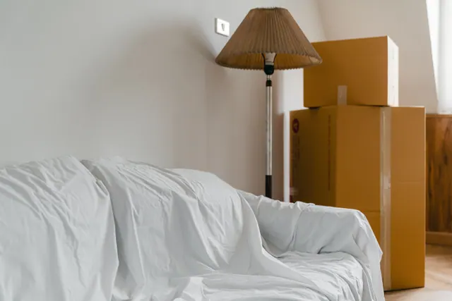 Sofá cubierto con una sábana junto a cajas de mudanza