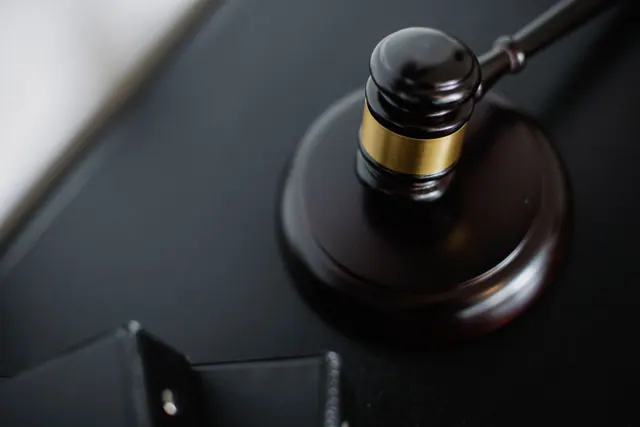 Mazo de juez de madera oscura con banda dorada sobre su base circular, símbolo de justicia y legalidad
