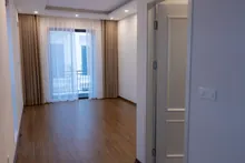Interior de apartamento moderno vacío con suelo de madera, cortinas beige y balcón con vistas a la ciudad
