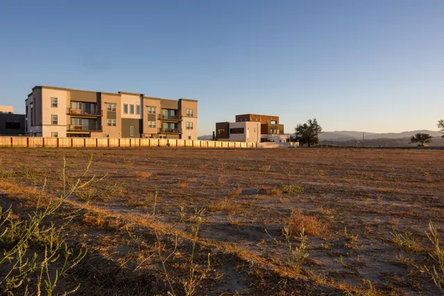 Edificios residenciales junto a un terreno baldío al atardecer