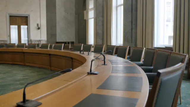 Sala de reuniones con mesas curvas de madera y sillas de cuero vacías
