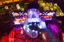 Vista aérea nocturna de un escenario de festival con público congregado