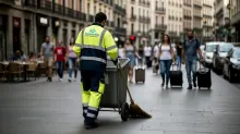 Trabajador de limpieza urbana barre una calle céntrica mientras transeúntes circulan