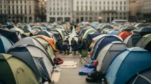Múltiples tiendas de campaña en una plaza urbana rodeada de edificios