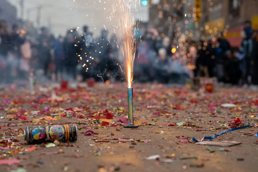 Fuegos artificiales encendidos en una calle llena de confeti
