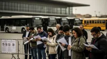 Un grupo de personas consulta documentos en una parada de autobuses