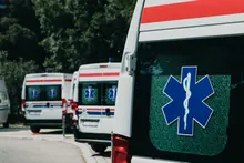 Varias ambulancias estacionadas en fila junto a un camino arbolado