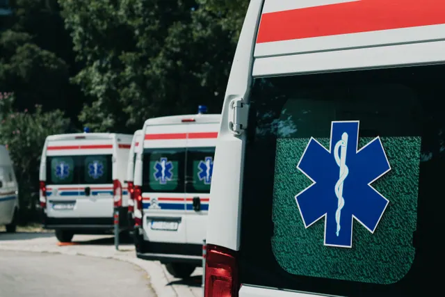 Varias ambulancias estacionadas en fila junto a un camino arbolado