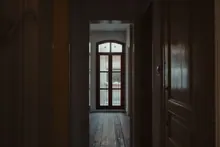 Pasillo en penumbra que da a una habitación con balcón