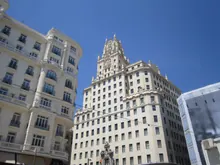 Fachada de un edificio señorial de piedra con grandes ventanales en una avenida urbana
