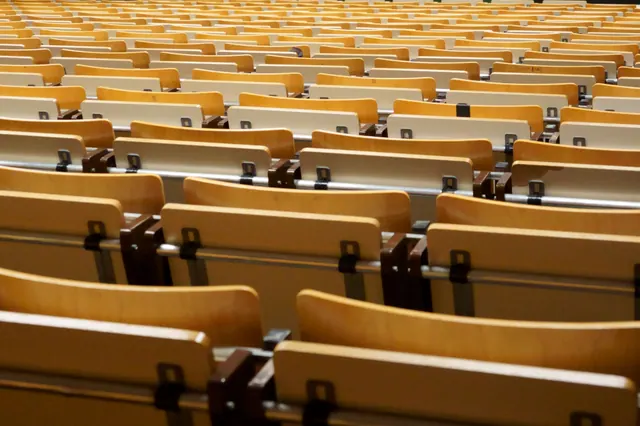 Filas de asientos de madera vacíos en un auditorio