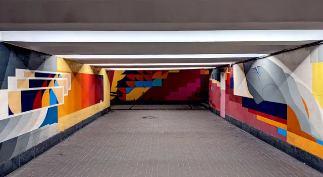 Túnel peatonal decorado con un mural geométrico de colores