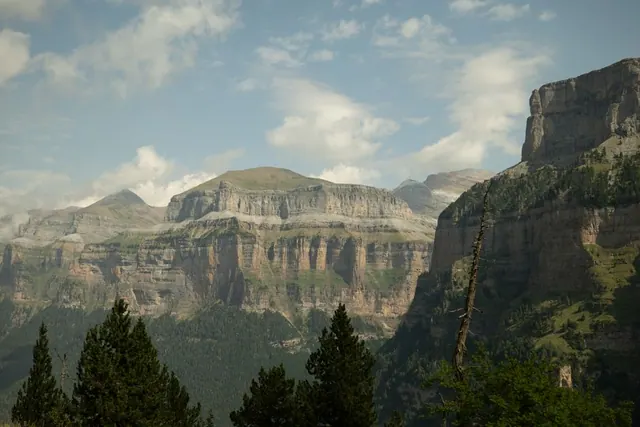 Sendero de montaña atravesando un cañón pirenaico con paredes rocosas verticales