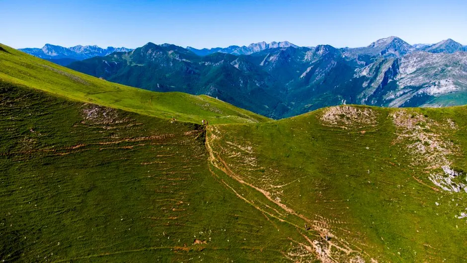 Senderista caminando por un sendero de montaña en España con vistas panorámicas