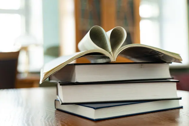 Pila de libros con las páginas de uno formando un corazón
