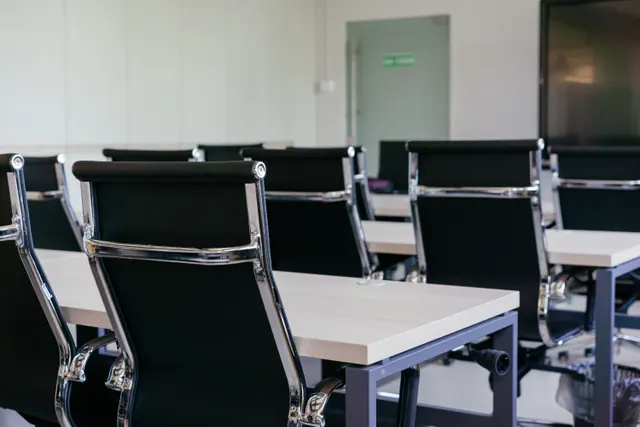 Sala de reuniones vacía con mesas y sillas de oficina