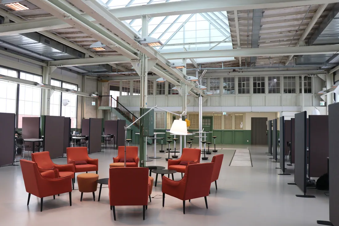 Sala diáfana con sillones y mesas de trabajo en una nave industrial