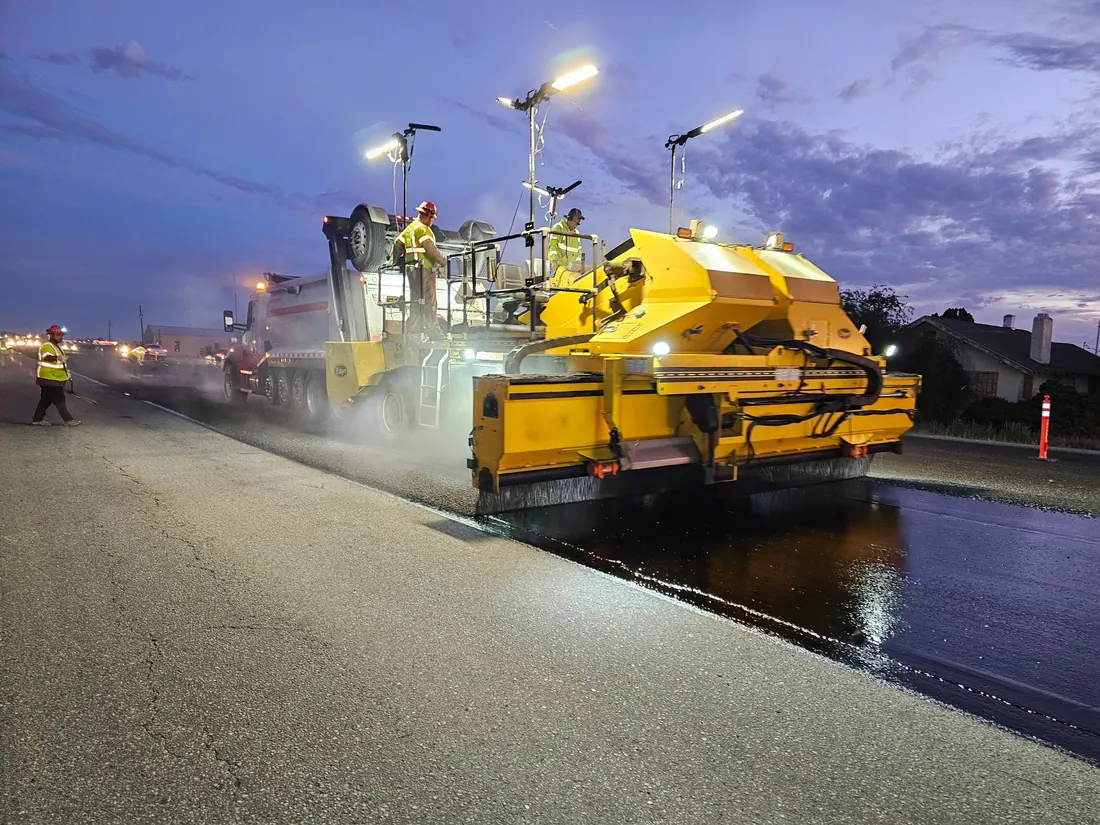 Calle estrecha con asfalto recién extendido, conos y vallas de obra