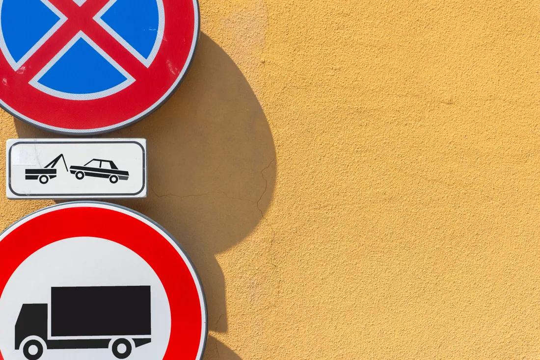 Señales de tráfico en una pared junto a un cartel de grúa