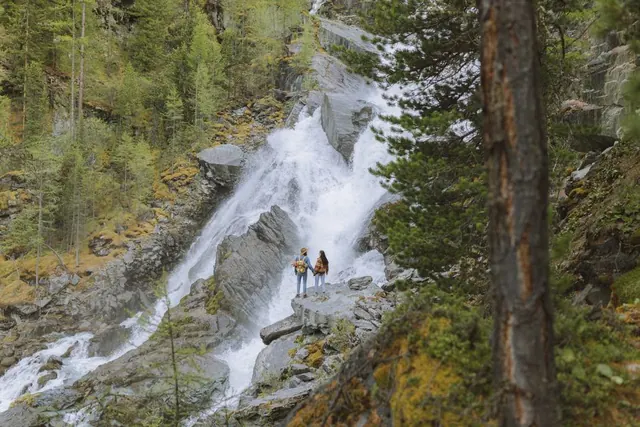 Cascada en bosque verde con senderista al fondo en España