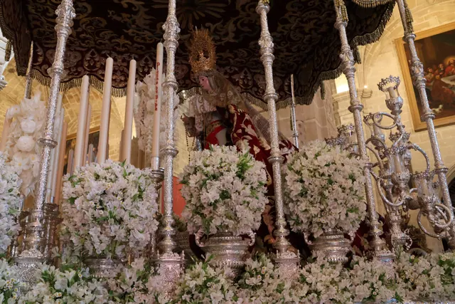 Un paso de Semana Santa con una virgen adornado con flores y candelabros